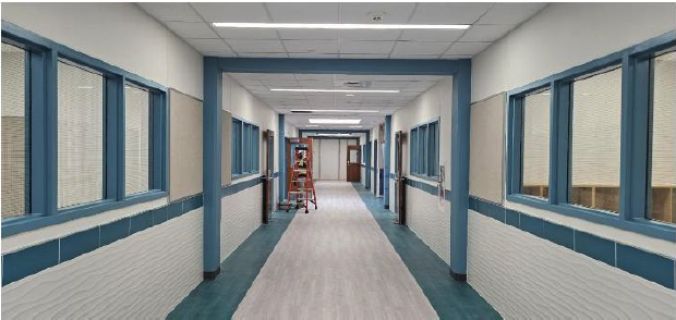 Wide hallway with blue accents, windows, and a ladder for maintenance.