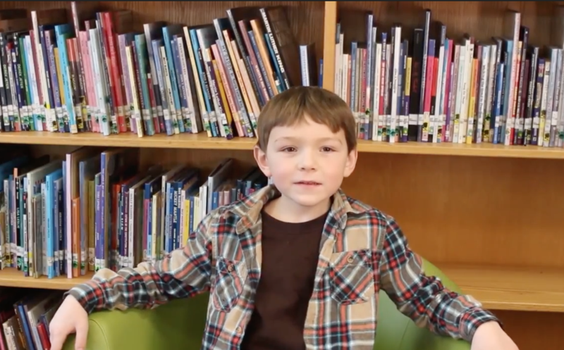 Child sitting in front of bookshelf