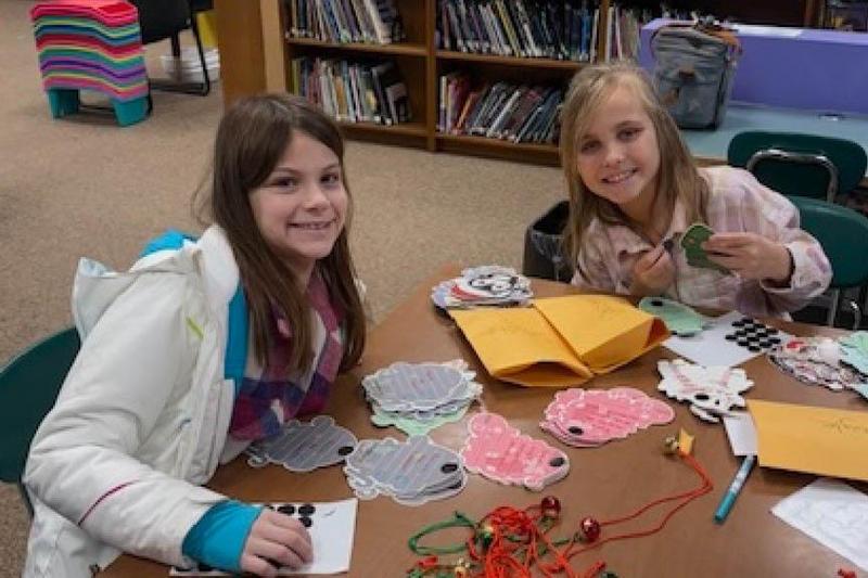 Kindness Club members Minda Raithel (grade 5) and Lydia Mellon (grade 3) assemble the Jingle Bell necklaces