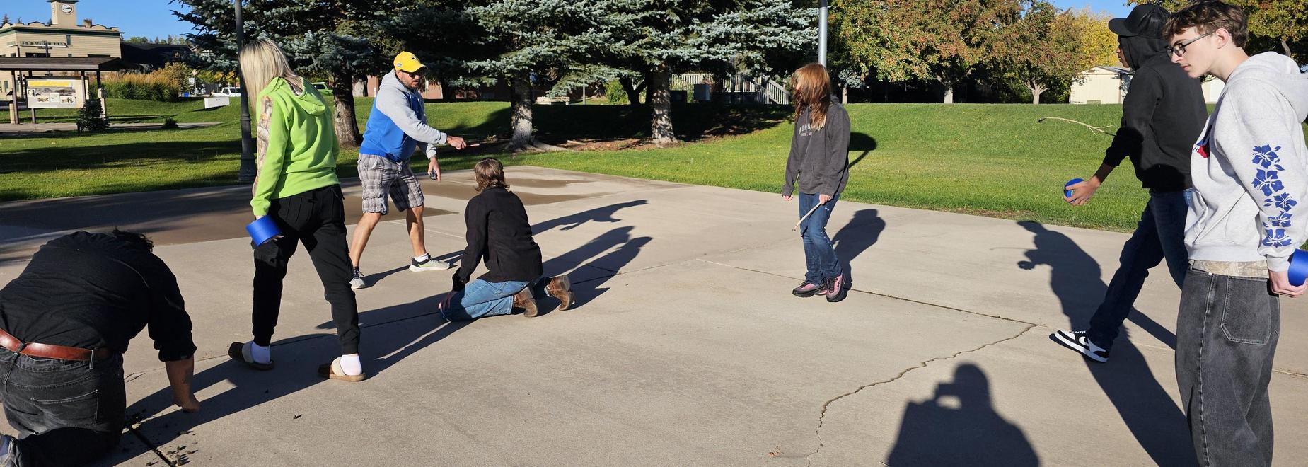 Group students painting lines on the basketball court at the park.