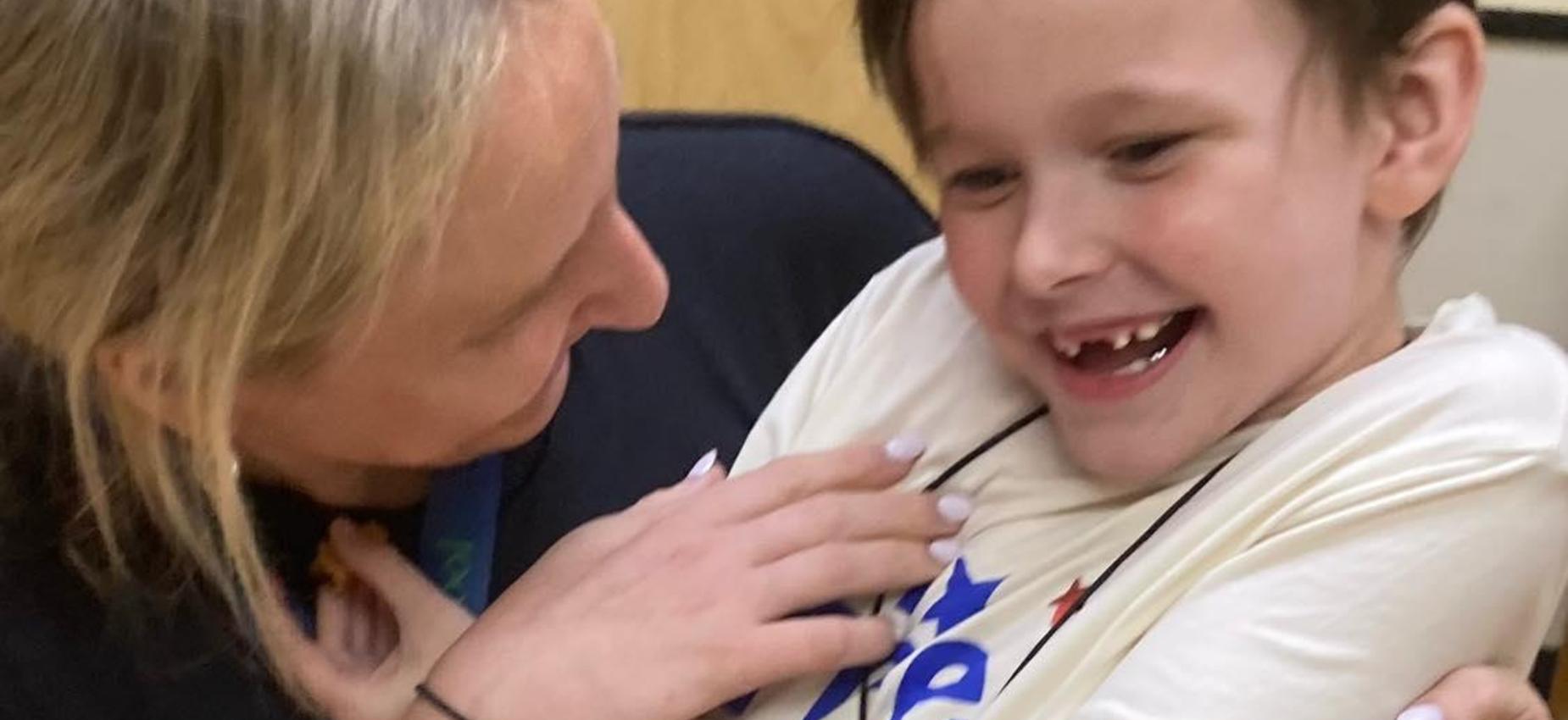 Caregiver holding a smiling boy during a playful moment.