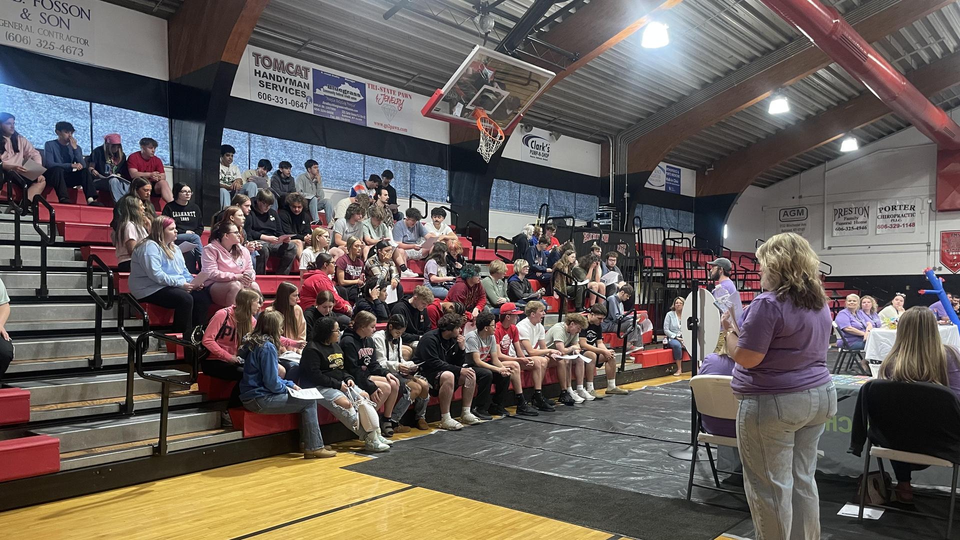 Audience seated in a gymnasium attending an event.