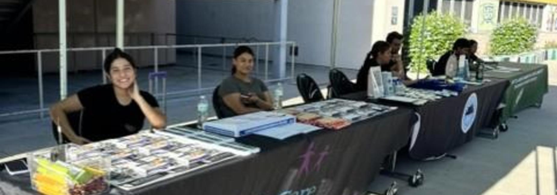 Students under gazebo with items on desk