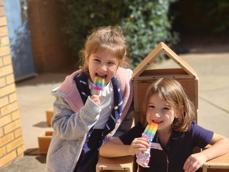 Two first grade girls eat their ice pops in honor of Rosh Chodesh.