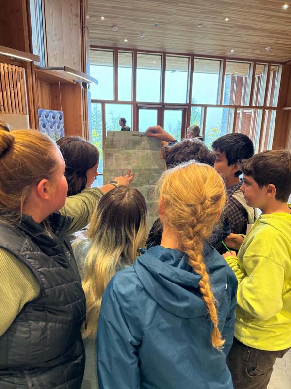 Group of young people examining a map indoors, engaged in discussion.