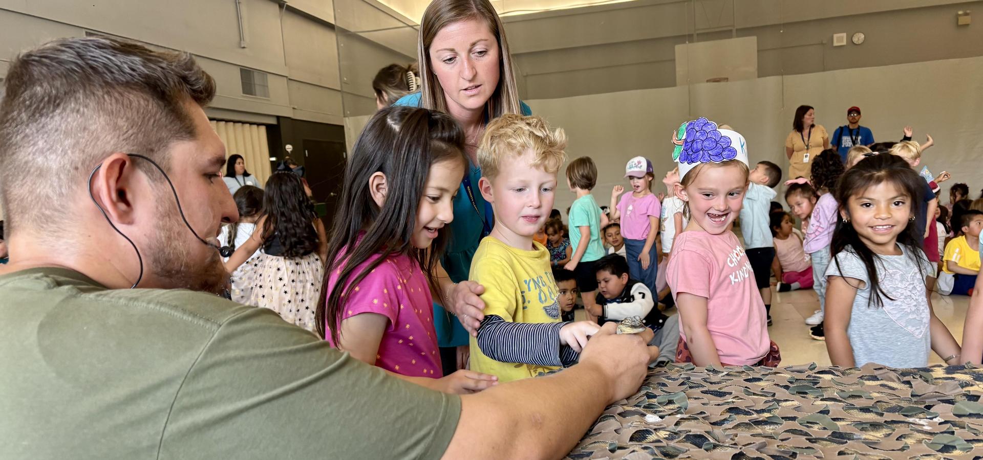 Adults and children engaging in a hands-on activity with a puppet in a classroom setting.