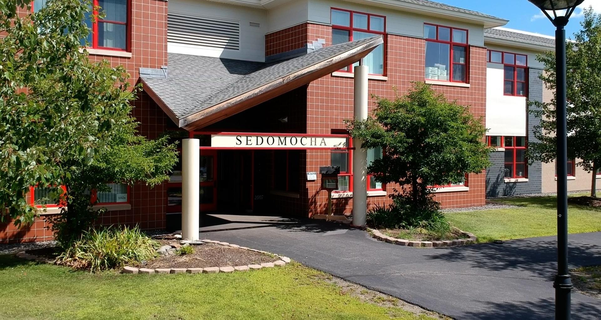 Building facade with red accents and a sign that reads 'SEDOMOCHA'.