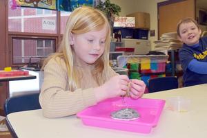 A student putting tiny beads on a wire