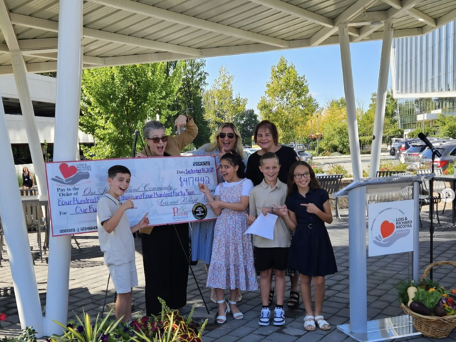 Children and adults celebrating with a large check for a community donation.