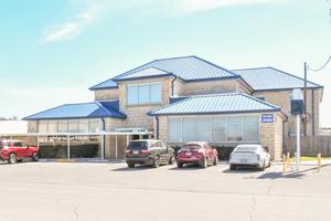 A stone building with a blue roof and several parked cars in front.