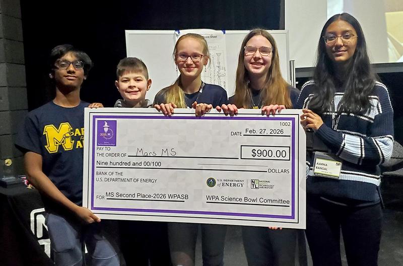 Five students holding an oversized check for $900