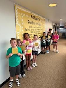 Photo of students in front of the Bellflower Energy Bus rules holding Golden Bus Tickets.
