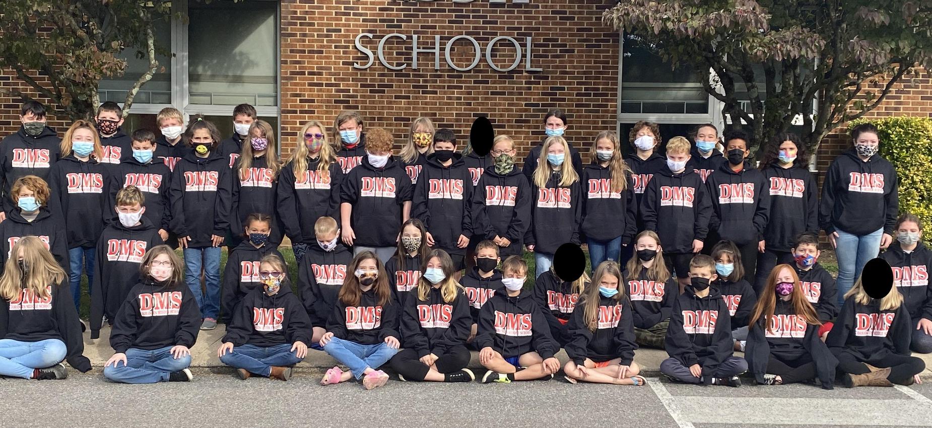 Students pose in front of a school.