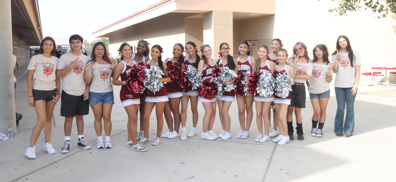 Group of cheerleaders and students posing together outdoors.
