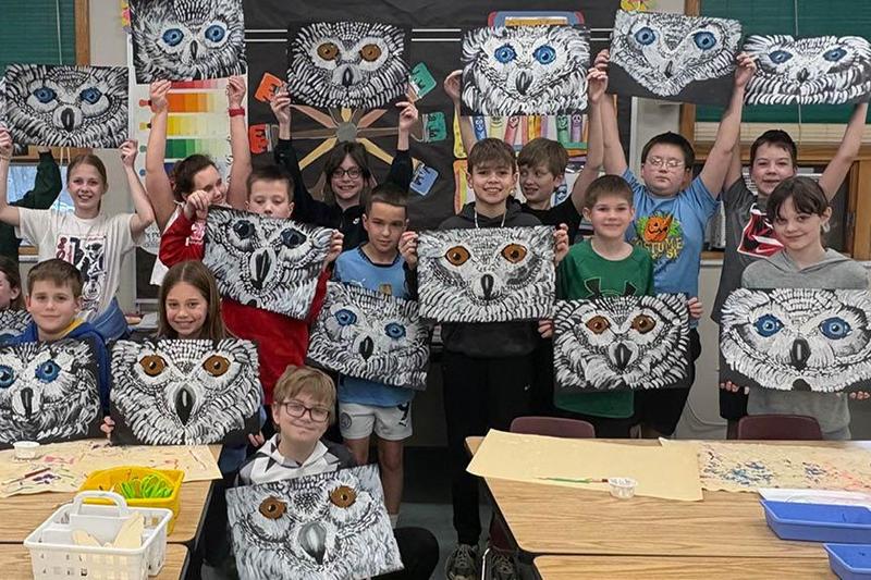 students hold up their finished art paintings