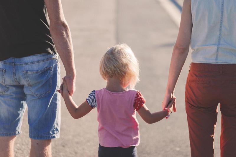 A couple holding hands with a child walks down a street