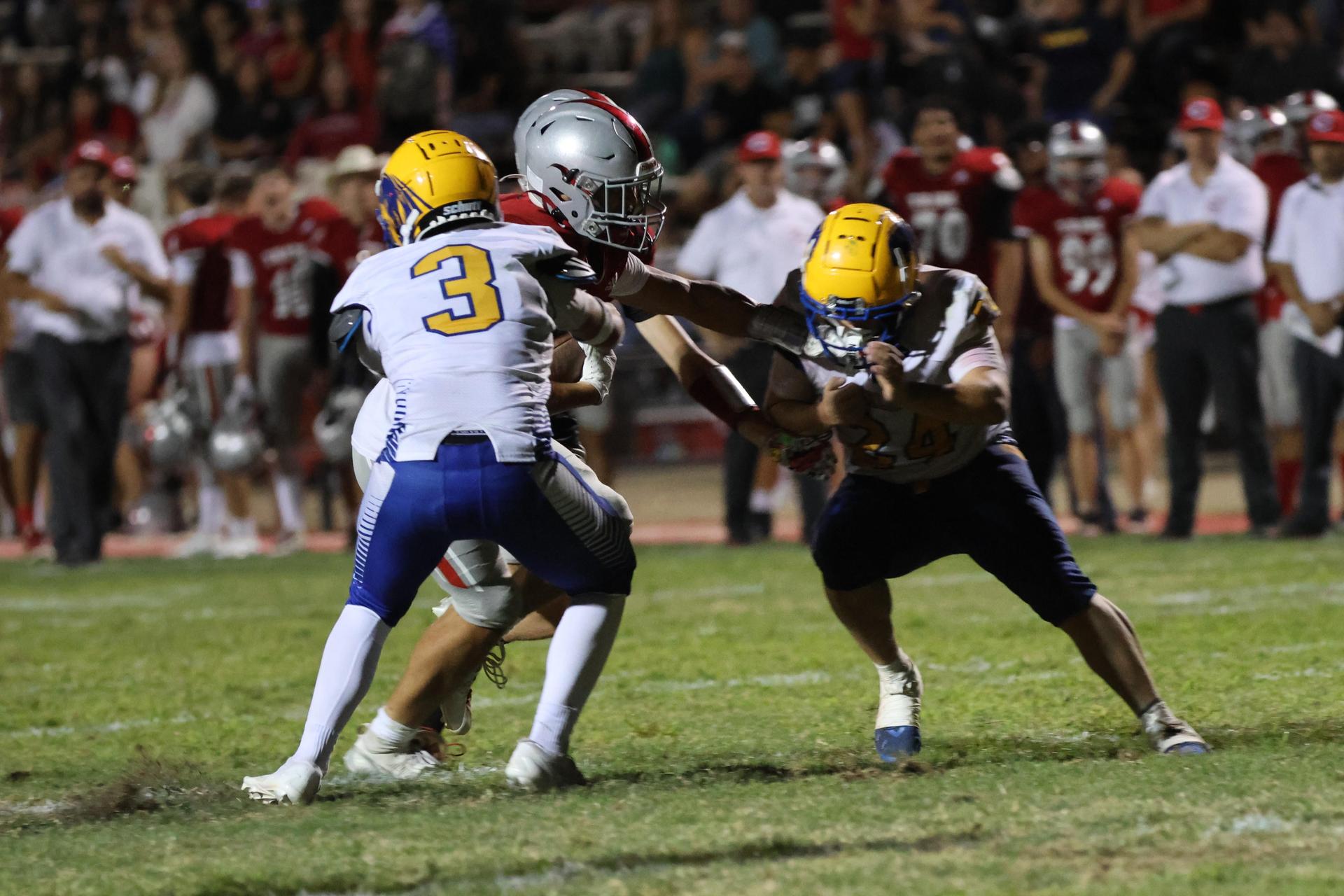 Varsity football players in action against Parlier 108