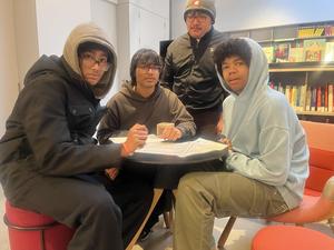 Four friends seated at a table reviewing documents in a cozy setting.
