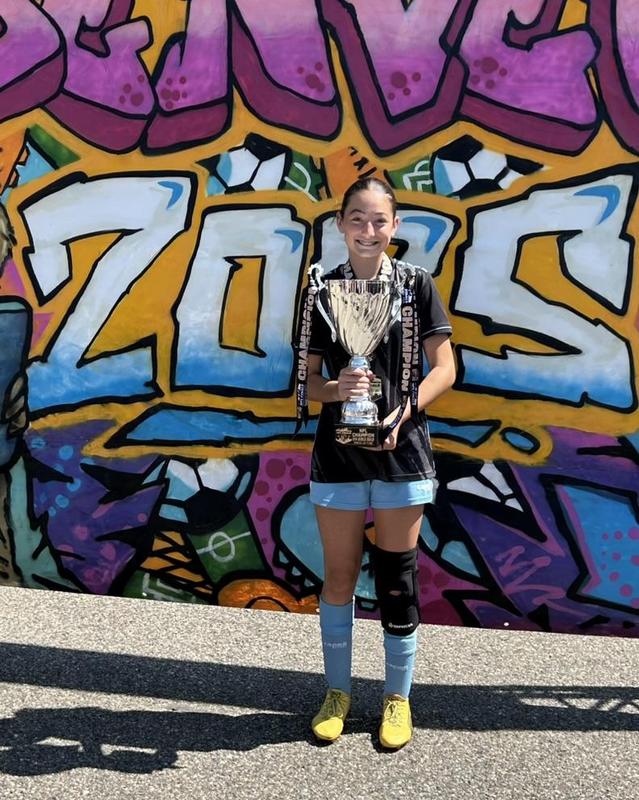 pic of a female soccer player in uniform holding a cup