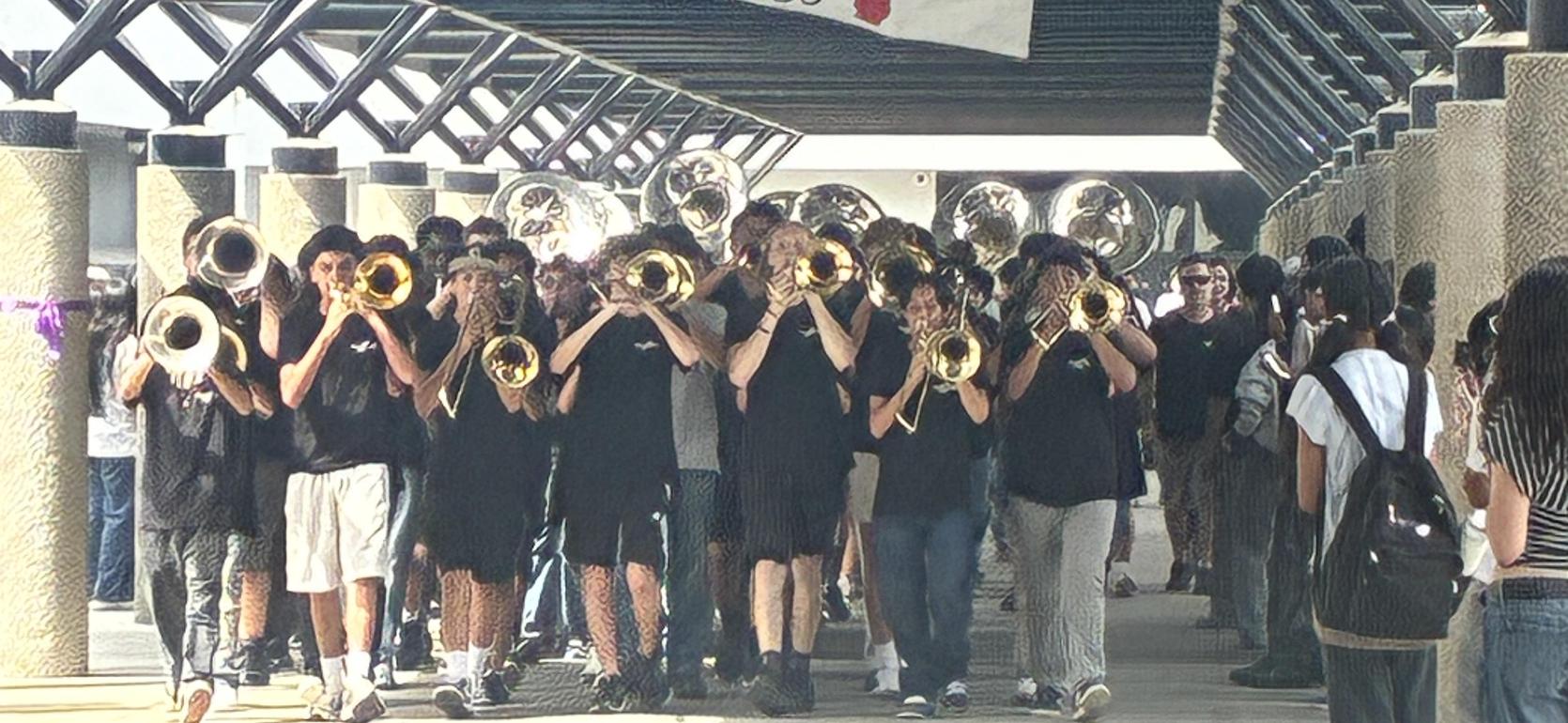 Marching band playing brass instruments in a hallway with spectators.