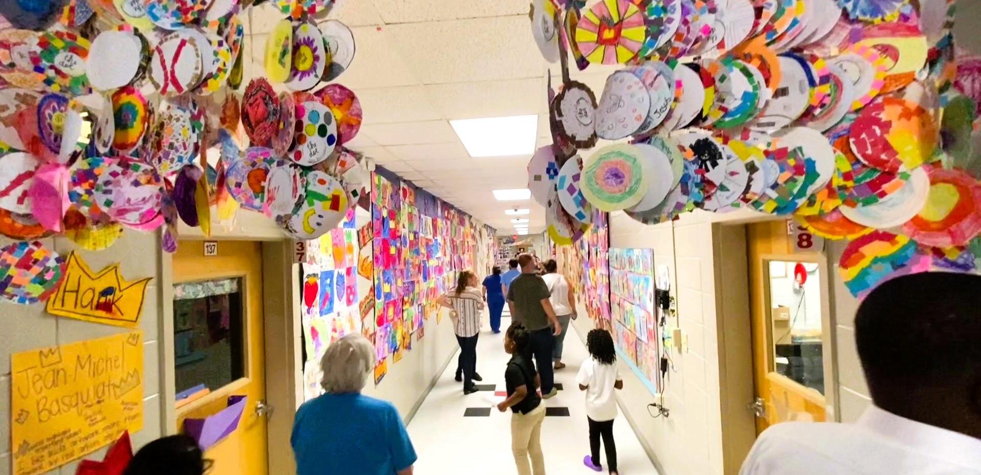 Busy hallway adorned with vibrant circular art displays and people walking through.