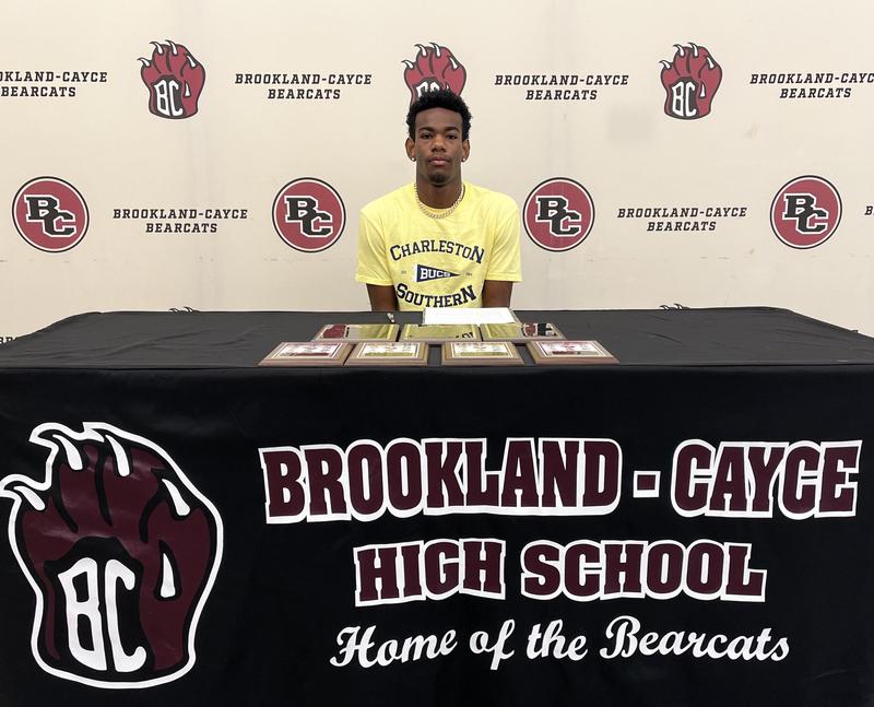 Aden Price seated at signing table
