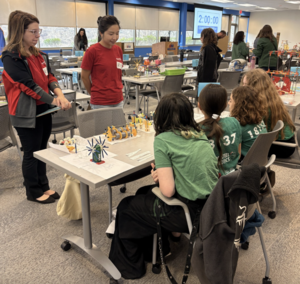 Four female students present their K'Nex prototype to judges at the STEM Design Challenge.