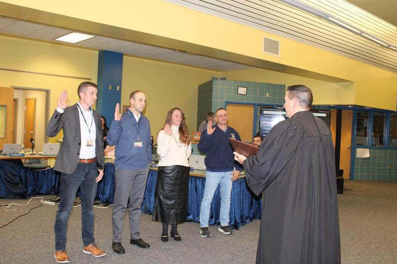 four school board members standing in front of judge with hand up swearing in