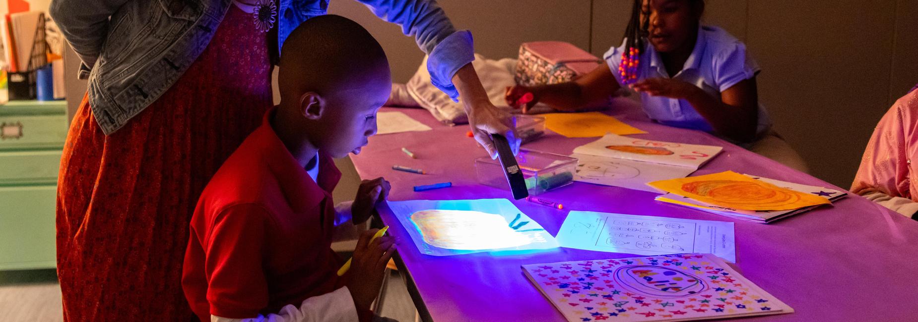 Students use a special light to do artwork