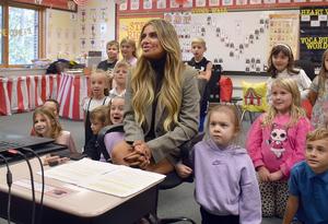 A teacher and young students all looking in one direction.