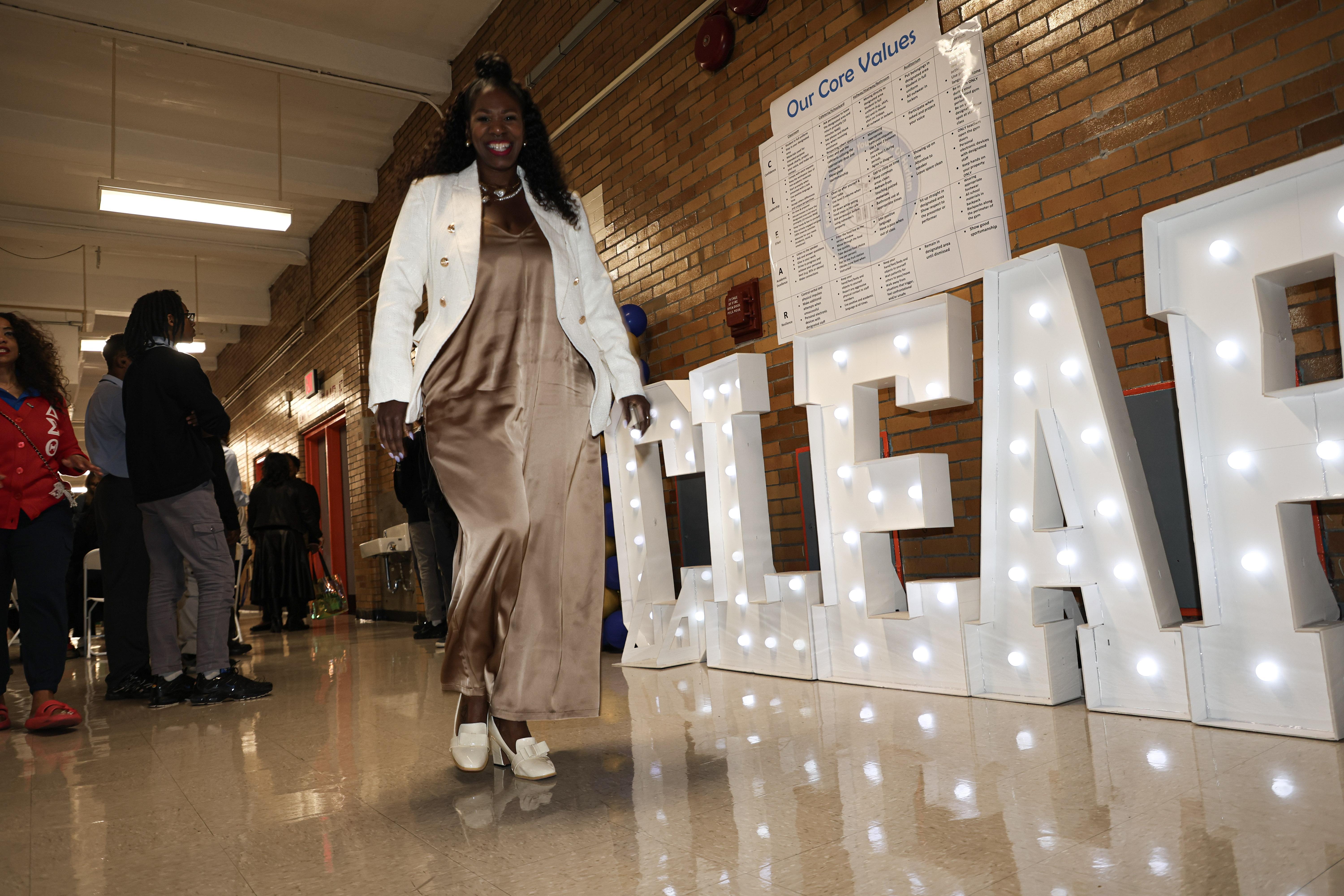 Person in a long dress walking past illuminated letters spelling 'CLEAR' in a hallway.
