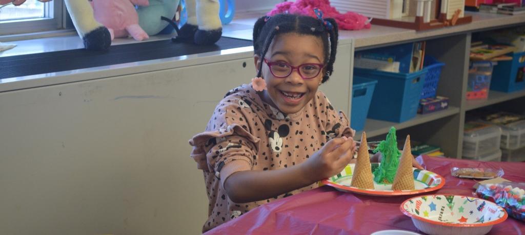 girl wearing glasses smiles at her frosted ice cream cone tree