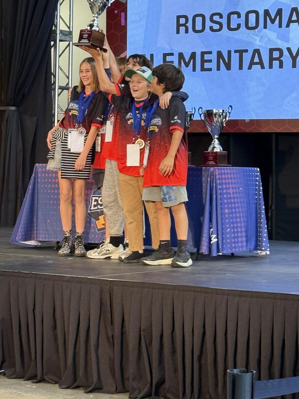 Esports team members holding up their 1st place trophy.
