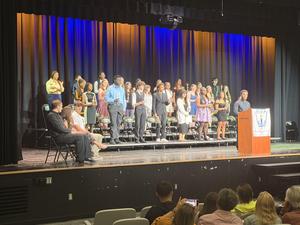 Students holding candles on stage during a National Honor Society induction ceremony.