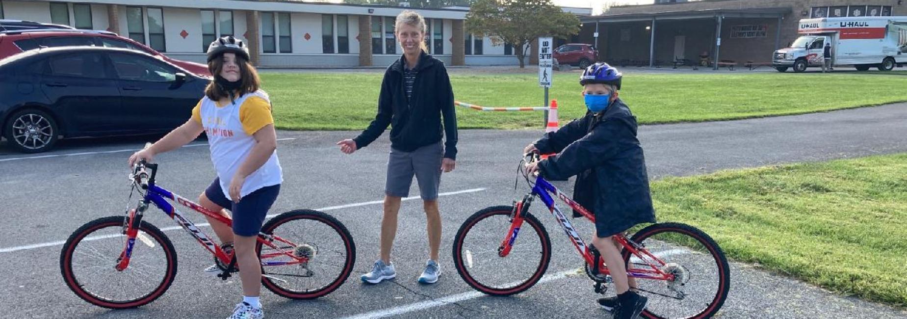 Photo of Mrs. Burchett, PE teacher, and two students riding bikes