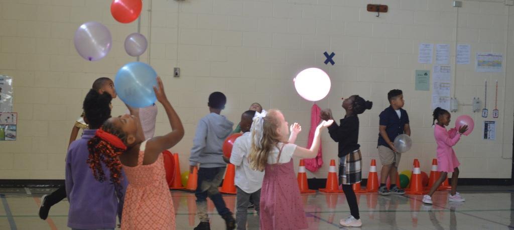 students strive to keep balloon afloat in gym