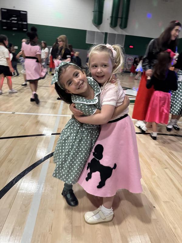 Two children hugging and wearing 1950's style clothes.