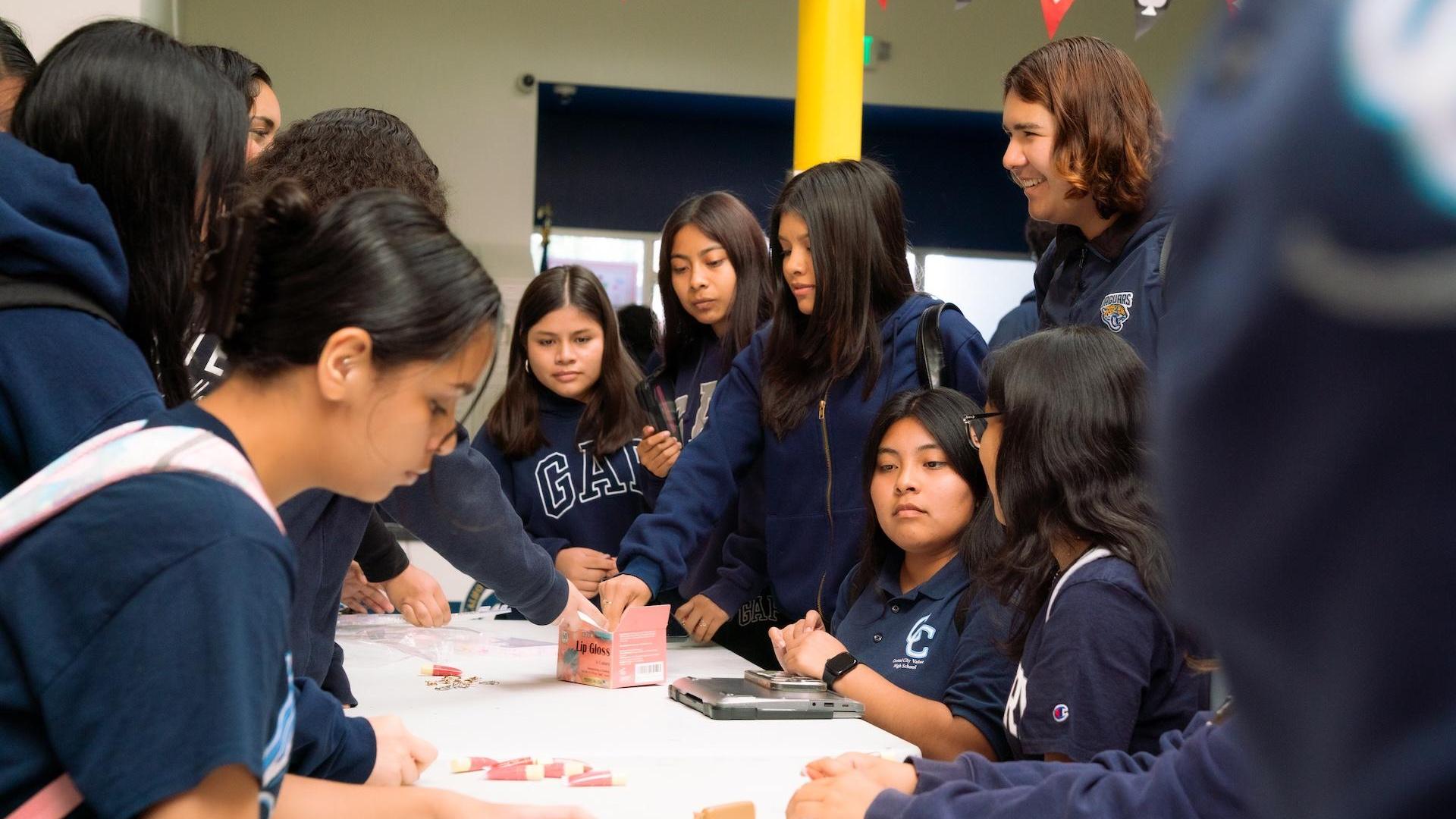 Group of girls collaborating around a table with various items.