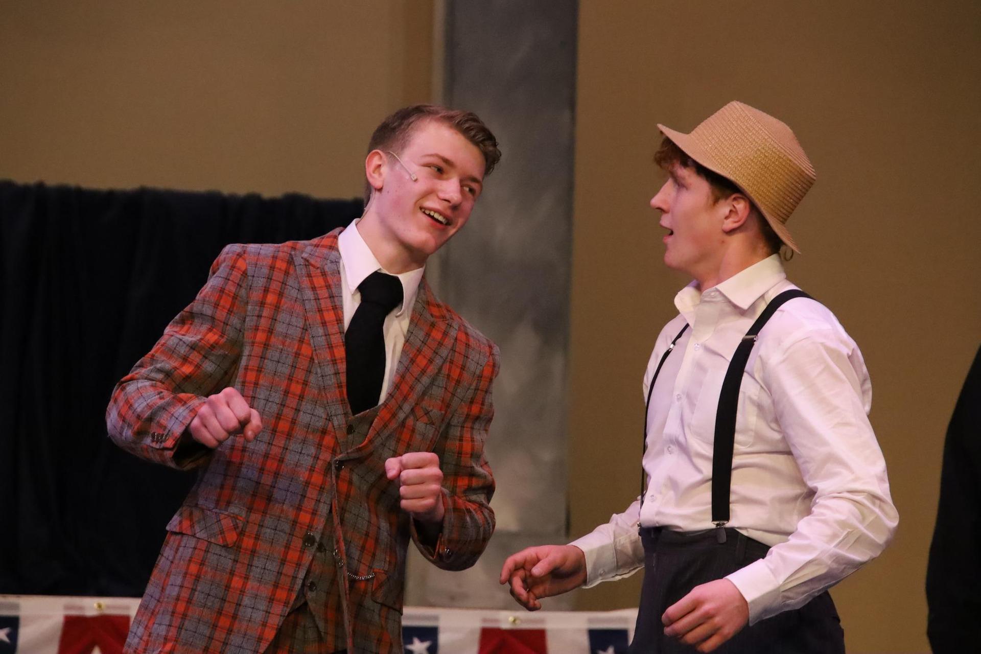 two high school students on a stage during a musical production