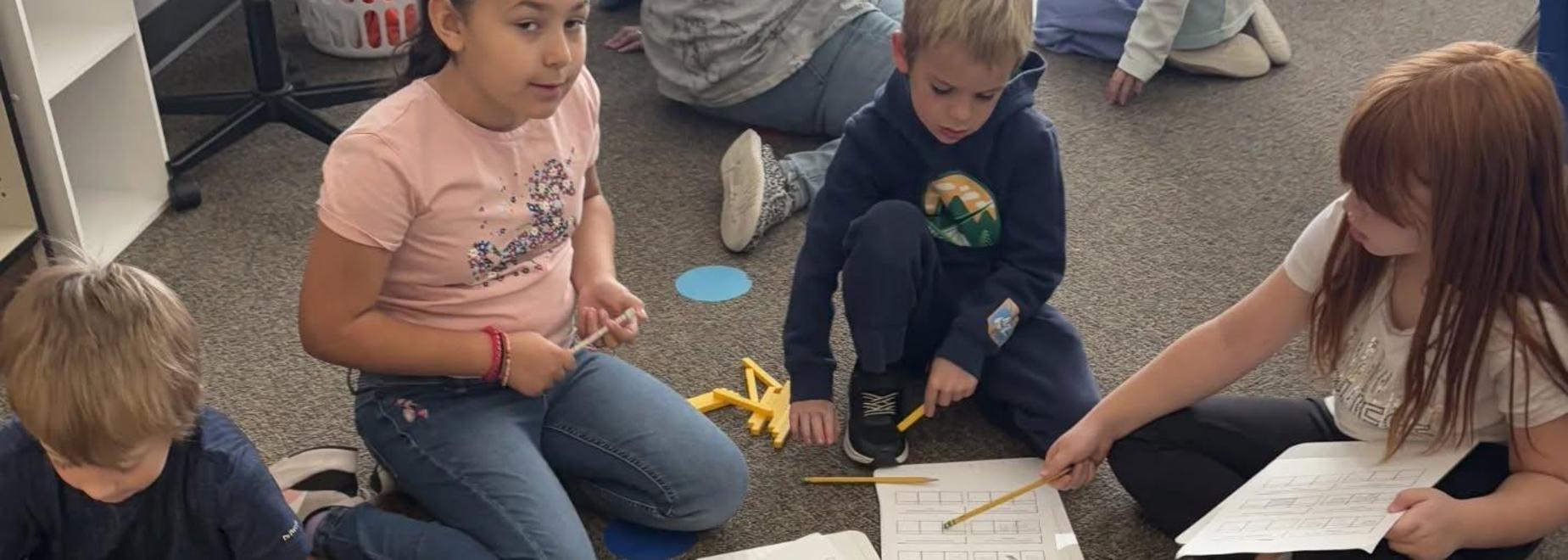 Children engaging in a classroom activity with papers and learning tools.
