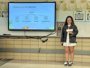 Student presents a survey method on a screen with visuals and notes.