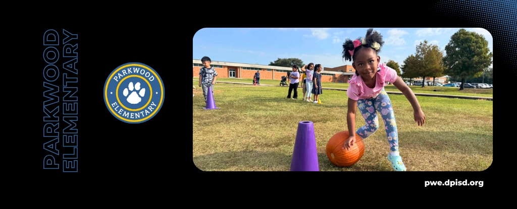 Children playing outside at Parkwood Elementary, with one girl rolling a basketball.
