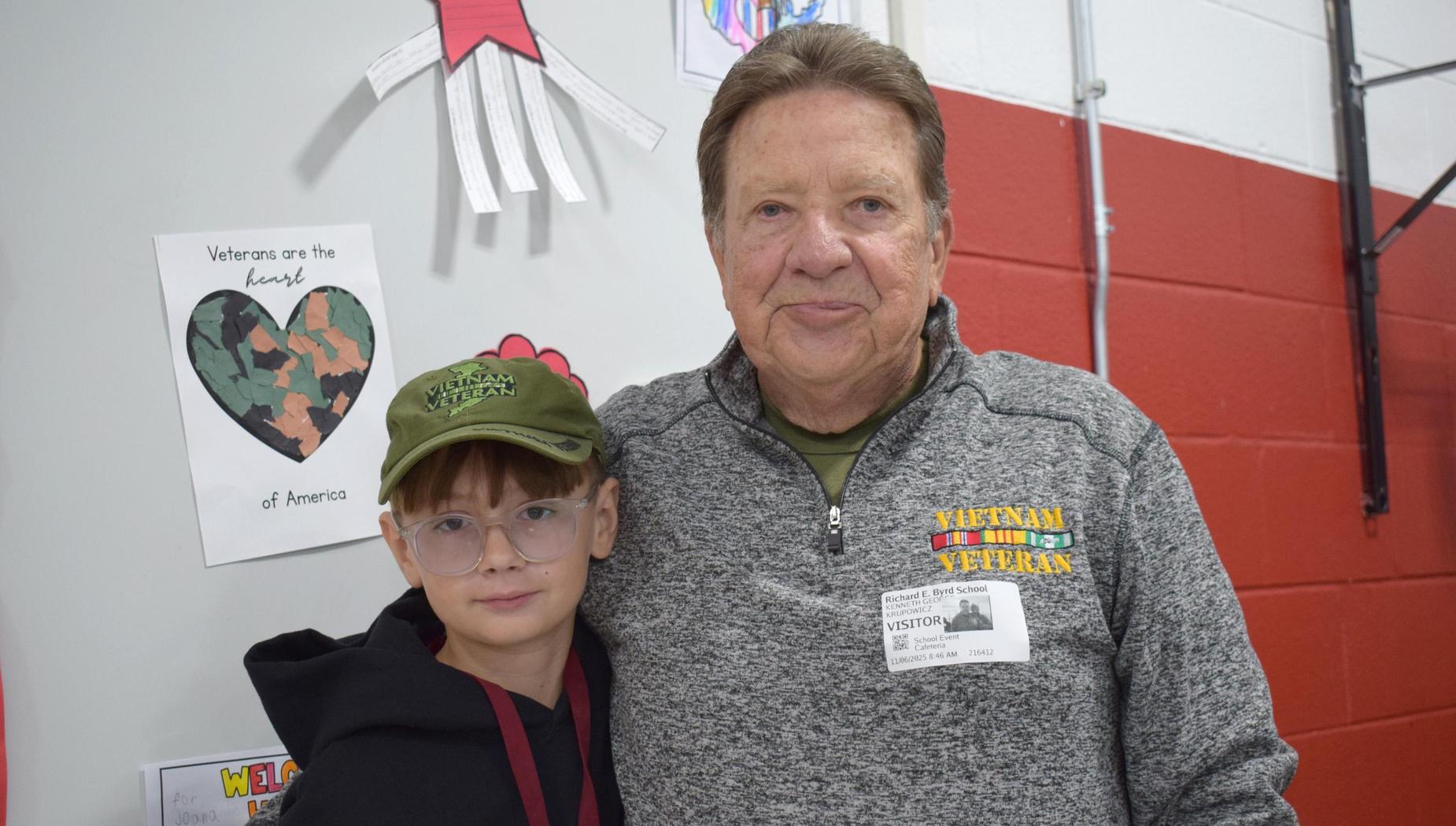 Senior veteran posing with a child at a Veterans Day celebration.