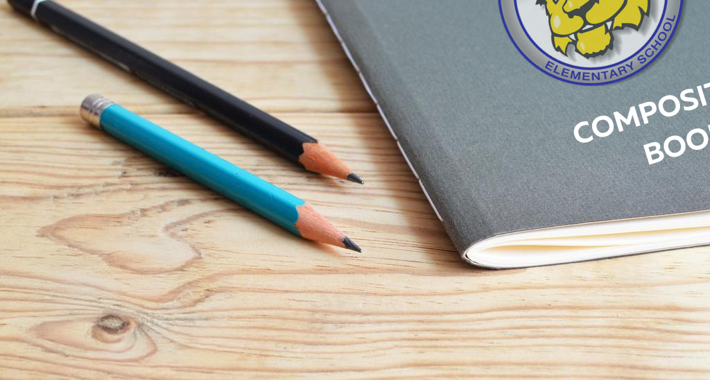 A gray composition book with two pencils resting on a wooden table.