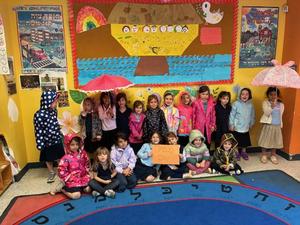Kindergarten girls pose wearing raincoats.