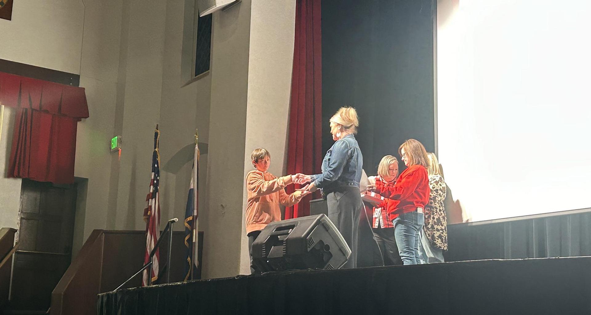 Several people on stage presenting awards or certificates at an event.
