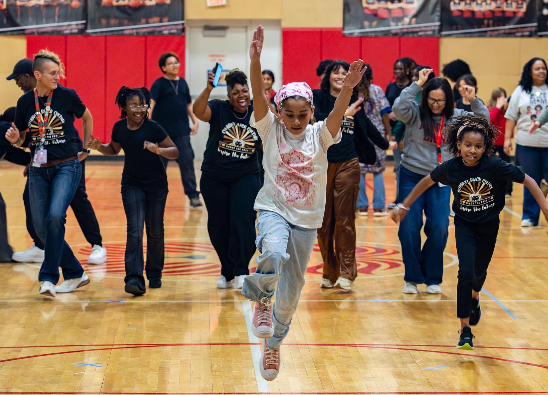 Students and staff dance on the gym floor