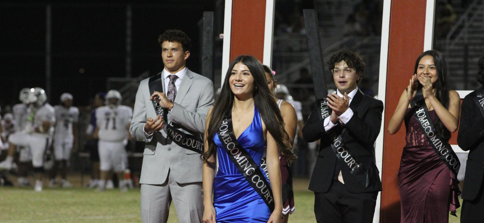 Students dressed in formal wear smiling during homecoming court.