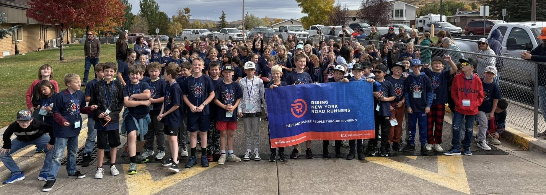 Group of young runners with a banner at a gathering in a park.