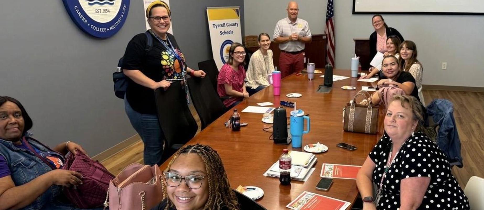 A group of diverse people seated around a conference table with snacks and drinks.